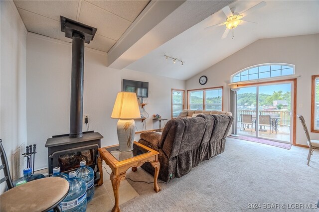 carpeted living room with lofted ceiling, ceiling fan, and a wood stove