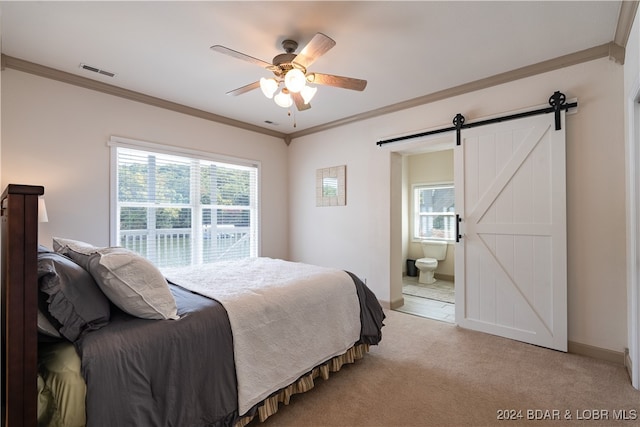 carpeted bedroom with a barn door, ensuite bath, multiple windows, and ceiling fan