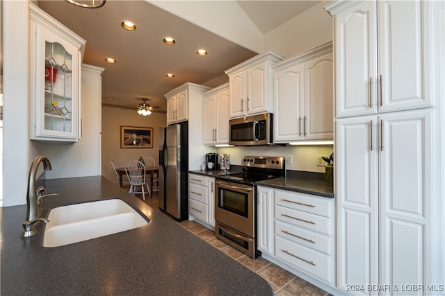 kitchen with ceiling fan, dark tile patterned flooring, sink, white cabinetry, and stainless steel appliances