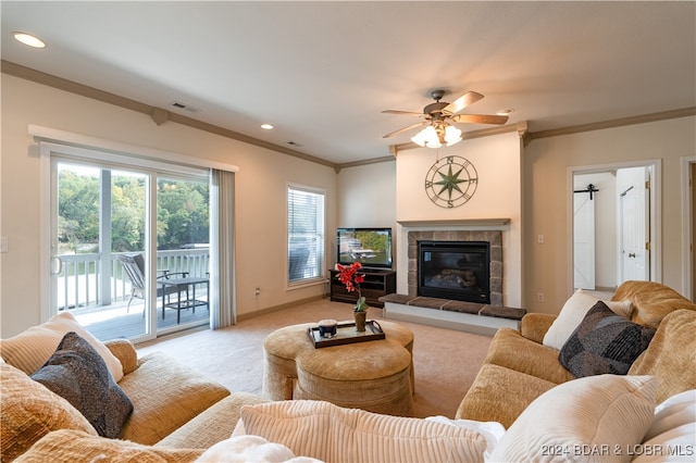 living room with ceiling fan, light carpet, a fireplace, a barn door, and ornamental molding