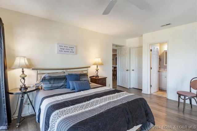 bedroom with wood-type flooring, ceiling fan, and ensuite bath