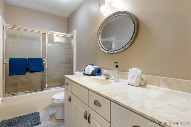 full bathroom with bath / shower combo with glass door, tile patterned floors, vanity, and toilet