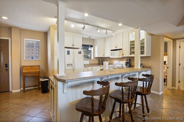 kitchen with white cabinets, hanging light fixtures, kitchen peninsula, white appliances, and a breakfast bar