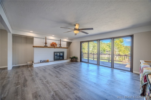 unfurnished living room with a textured ceiling, wood-type flooring, and ceiling fan