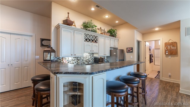 kitchen with appliances with stainless steel finishes, kitchen peninsula, white cabinetry, and a kitchen bar