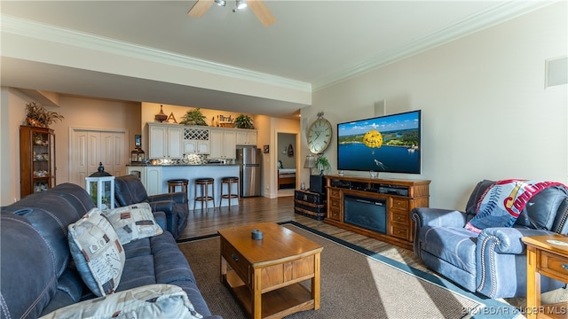 living room with ceiling fan, ornamental molding, and dark hardwood / wood-style floors