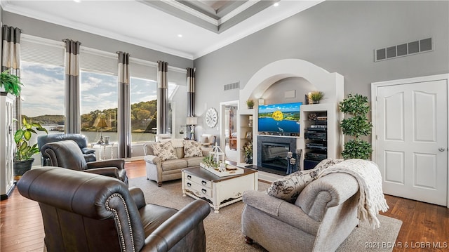 living room with a towering ceiling, ornamental molding, hardwood / wood-style flooring, and a healthy amount of sunlight