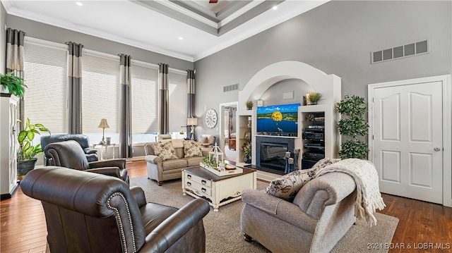 living room with crown molding, dark hardwood / wood-style floors, and a towering ceiling