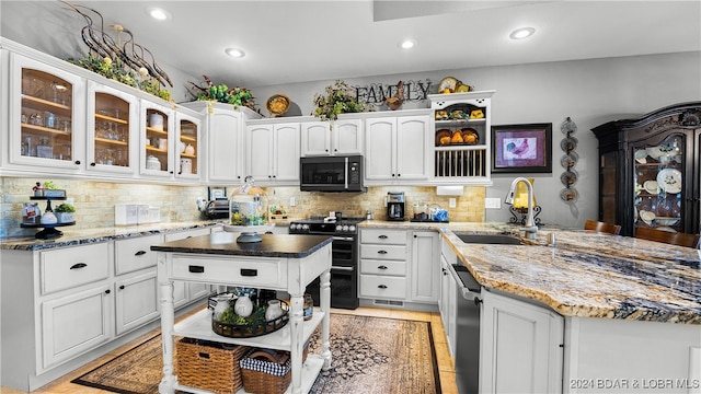 kitchen with white cabinets, tasteful backsplash, dark stone counters, black appliances, and sink