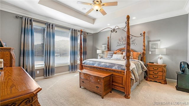 carpeted bedroom featuring ceiling fan, ornamental molding, and a tray ceiling