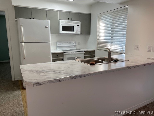 kitchen with kitchen peninsula, white appliances, sink, and light carpet