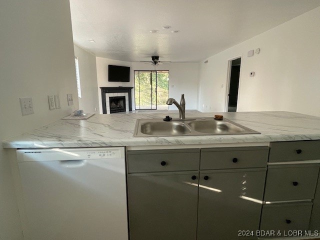 kitchen featuring dishwasher, kitchen peninsula, sink, and light stone countertops