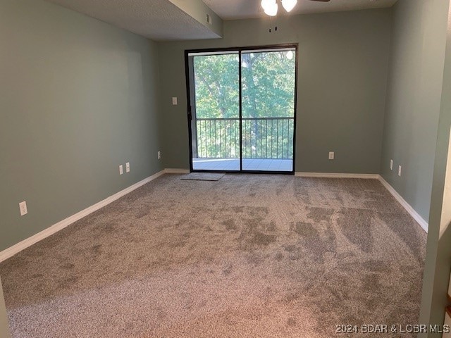 carpeted spare room featuring ceiling fan