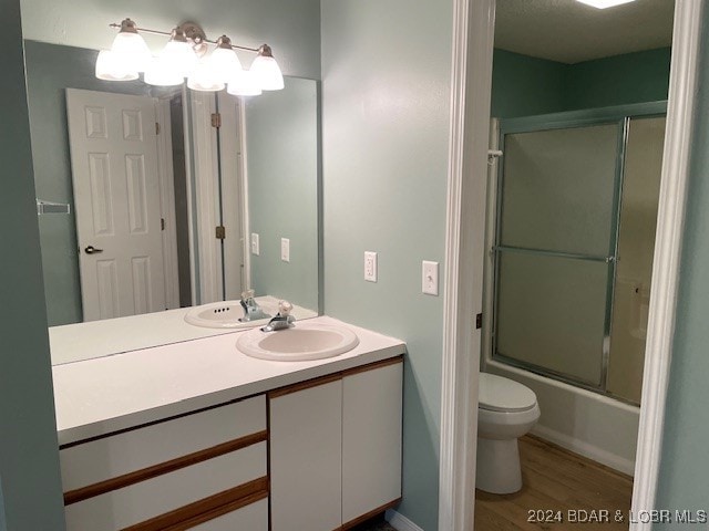 full bathroom featuring hardwood / wood-style floors, shower / bath combination with glass door, toilet, and vanity