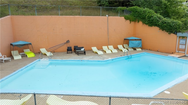 community pool with a patio area and fence