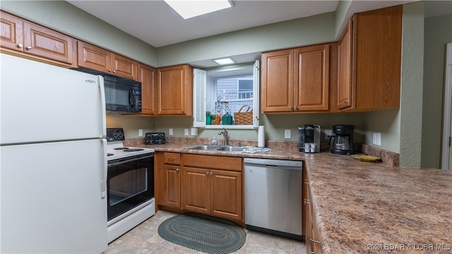 kitchen featuring electric range, freestanding refrigerator, a sink, black microwave, and dishwasher