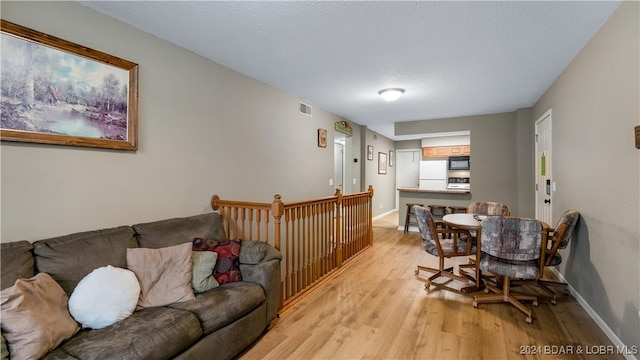 living area with visible vents, baseboards, and light wood-style floors