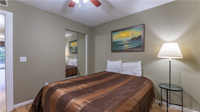 bedroom featuring wood finished floors, visible vents, baseboards, and ceiling fan