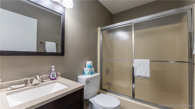 full bath featuring shower / bath combination with glass door, toilet, vanity, and a textured wall