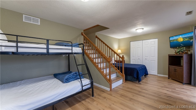 bedroom with wood finished floors, visible vents, and a textured ceiling