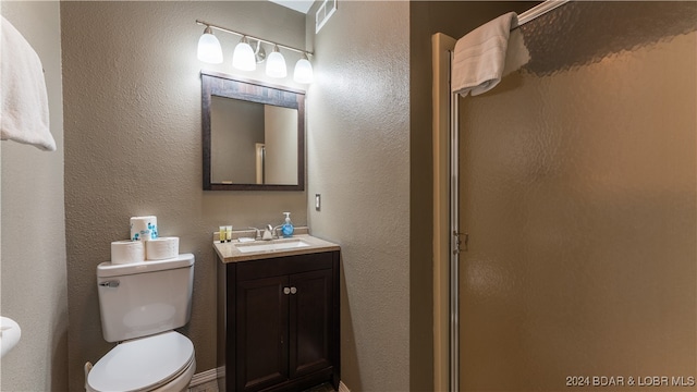 bathroom with visible vents, vanity, toilet, and a shower stall