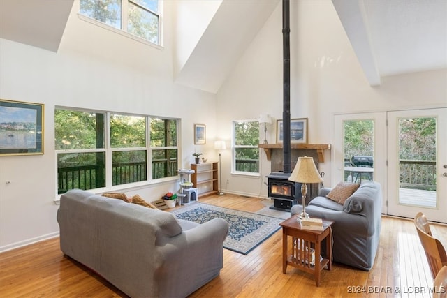 living room with light hardwood / wood-style floors, high vaulted ceiling, and a wood stove