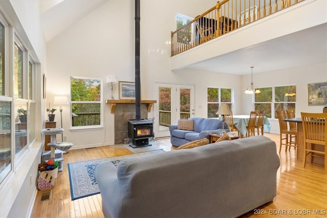 living room featuring a wood stove, a chandelier, high vaulted ceiling, and light wood-type flooring