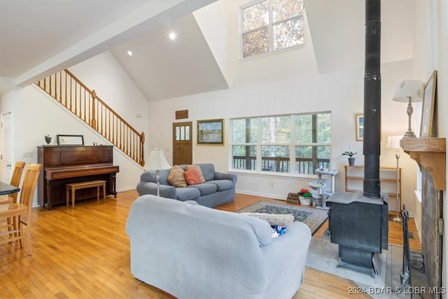 living room with high vaulted ceiling, light wood-type flooring, and a wood stove