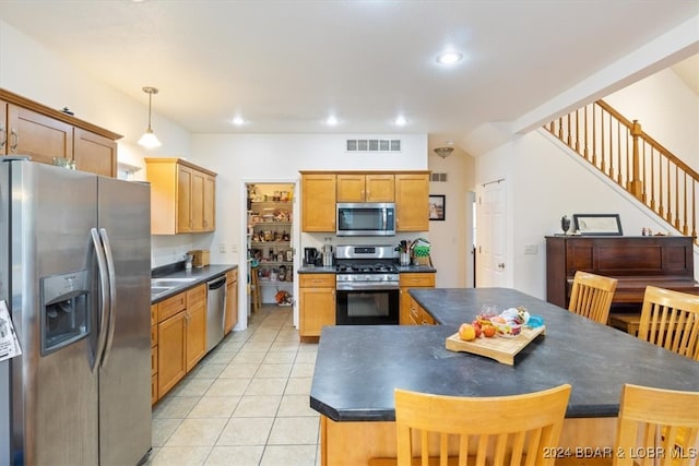 kitchen featuring appliances with stainless steel finishes, light tile patterned flooring, a kitchen island, and hanging light fixtures