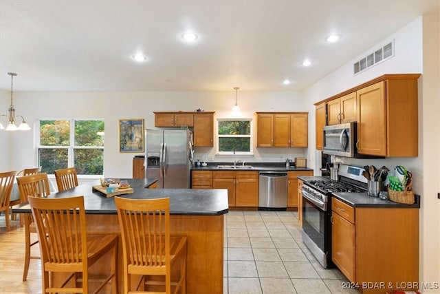 kitchen with appliances with stainless steel finishes, a center island, hanging light fixtures, and a wealth of natural light