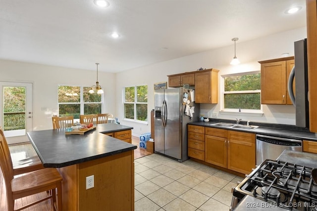 kitchen with a kitchen island, appliances with stainless steel finishes, decorative light fixtures, and a healthy amount of sunlight