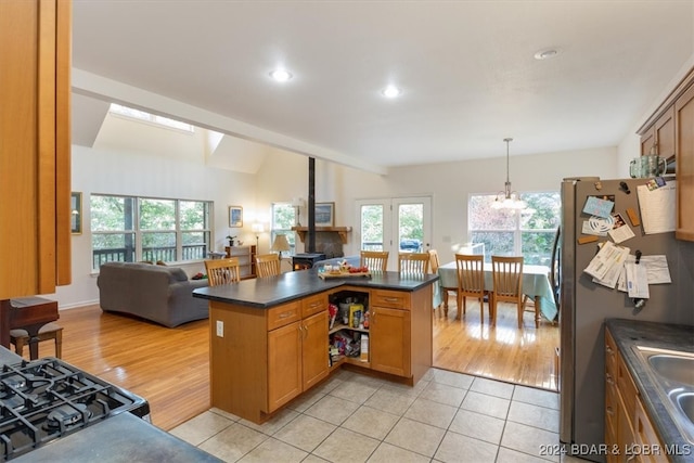 kitchen featuring lofted ceiling, kitchen peninsula, pendant lighting, light wood-type flooring, and stainless steel refrigerator