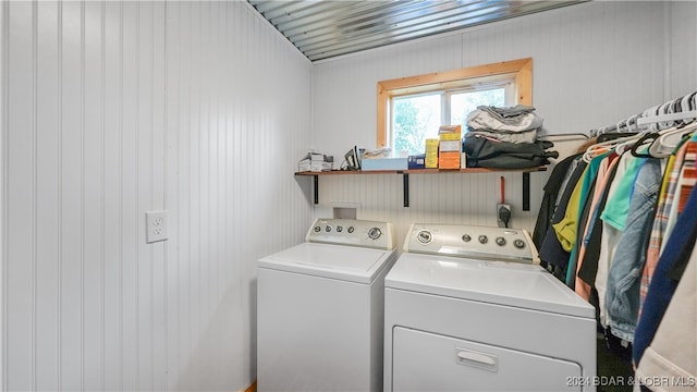 laundry area featuring wood walls and washing machine and dryer