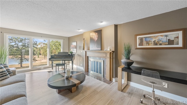 living room with light hardwood / wood-style floors, a textured ceiling, and a fireplace