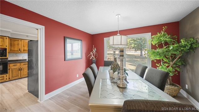 dining room with a textured ceiling and light hardwood / wood-style floors