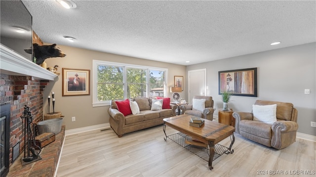 living room with a textured ceiling, light hardwood / wood-style flooring, and a fireplace