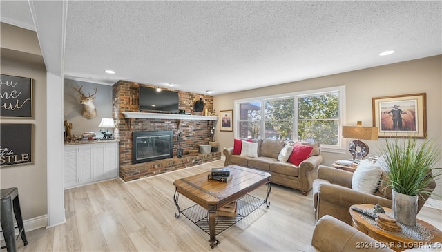 living room with light hardwood / wood-style floors, a textured ceiling, and a fireplace