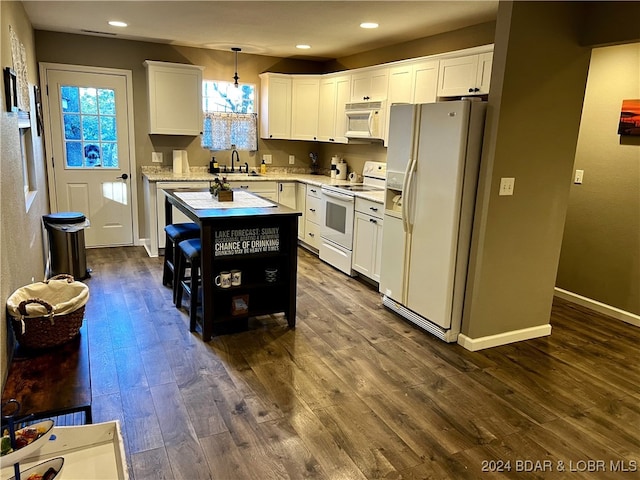 kitchen featuring white appliances, a kitchen island, hanging light fixtures, white cabinetry, and dark hardwood / wood-style floors