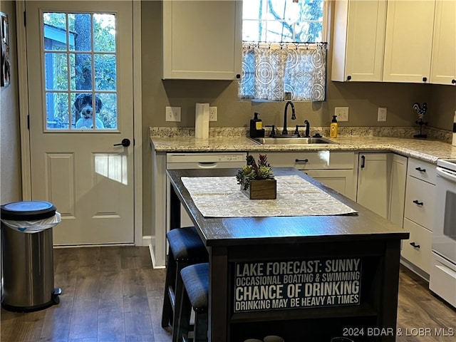 kitchen with a center island, light stone countertops, sink, and dark wood-type flooring