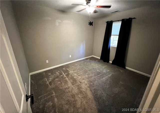 unfurnished room featuring dark carpet and ceiling fan