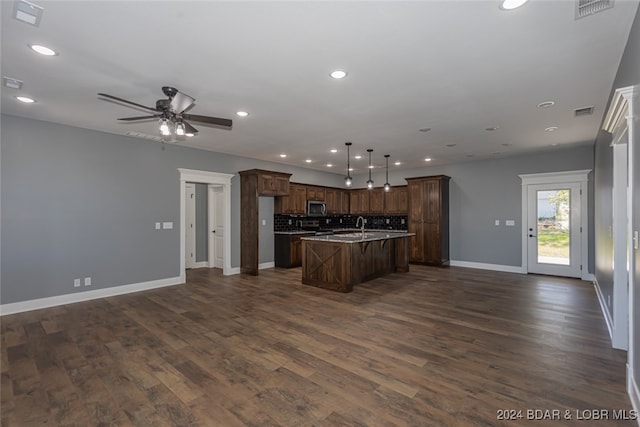 kitchen featuring sink, dark hardwood / wood-style flooring, ceiling fan, pendant lighting, and a center island with sink