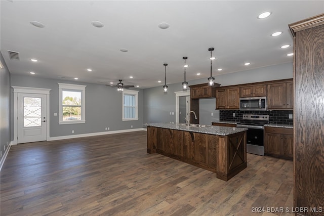 kitchen featuring light stone counters, stainless steel appliances, dark hardwood / wood-style flooring, and a kitchen island with sink