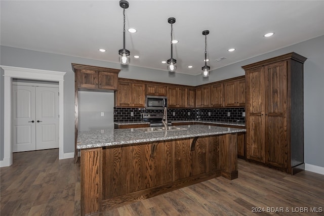 kitchen featuring dark stone countertops, appliances with stainless steel finishes, dark hardwood / wood-style flooring, and decorative backsplash