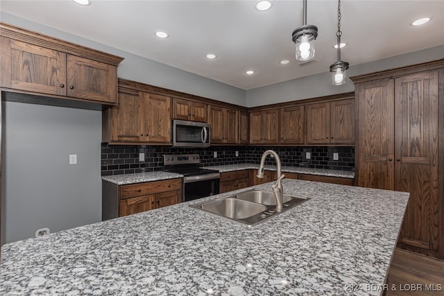 kitchen featuring appliances with stainless steel finishes, sink, pendant lighting, decorative backsplash, and dark hardwood / wood-style floors