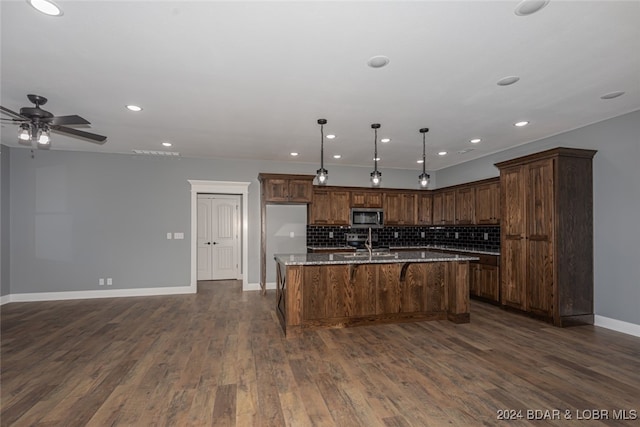 kitchen featuring light stone counters, dark wood-type flooring, backsplash, and pendant lighting