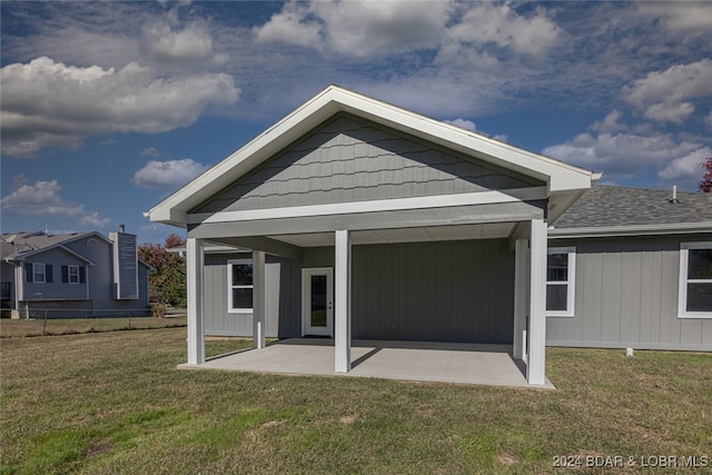 back of house with a patio and a lawn