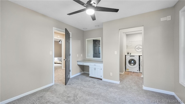 unfurnished bedroom with built in desk, washer / clothes dryer, ceiling fan, and light colored carpet