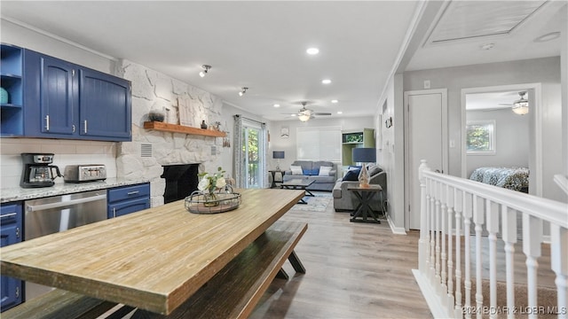 kitchen featuring blue cabinetry, ceiling fan, dishwasher, light stone counters, and light hardwood / wood-style floors