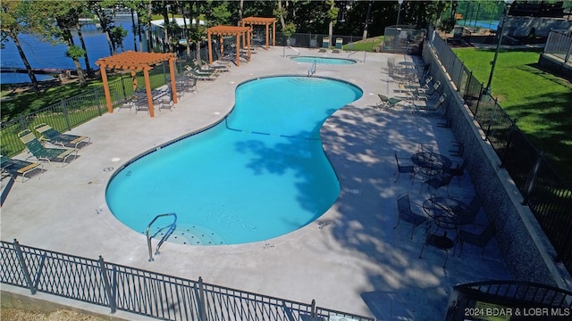 view of swimming pool featuring a hot tub, a patio area, a lawn, and a water view