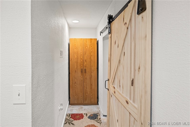 hallway featuring a barn door and a textured ceiling